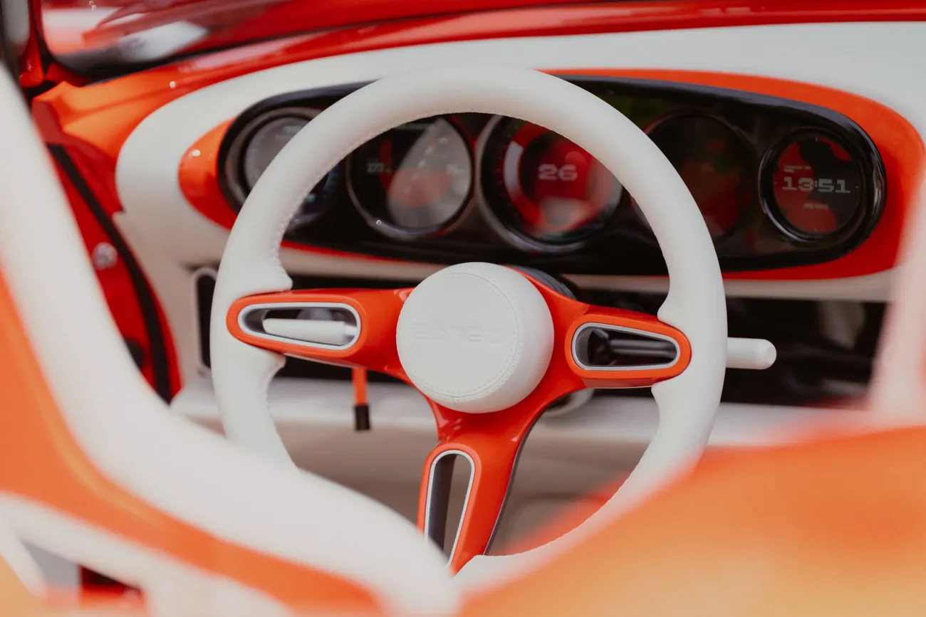 Cream-rimmed steering wheel with orange spokes in front of round dials