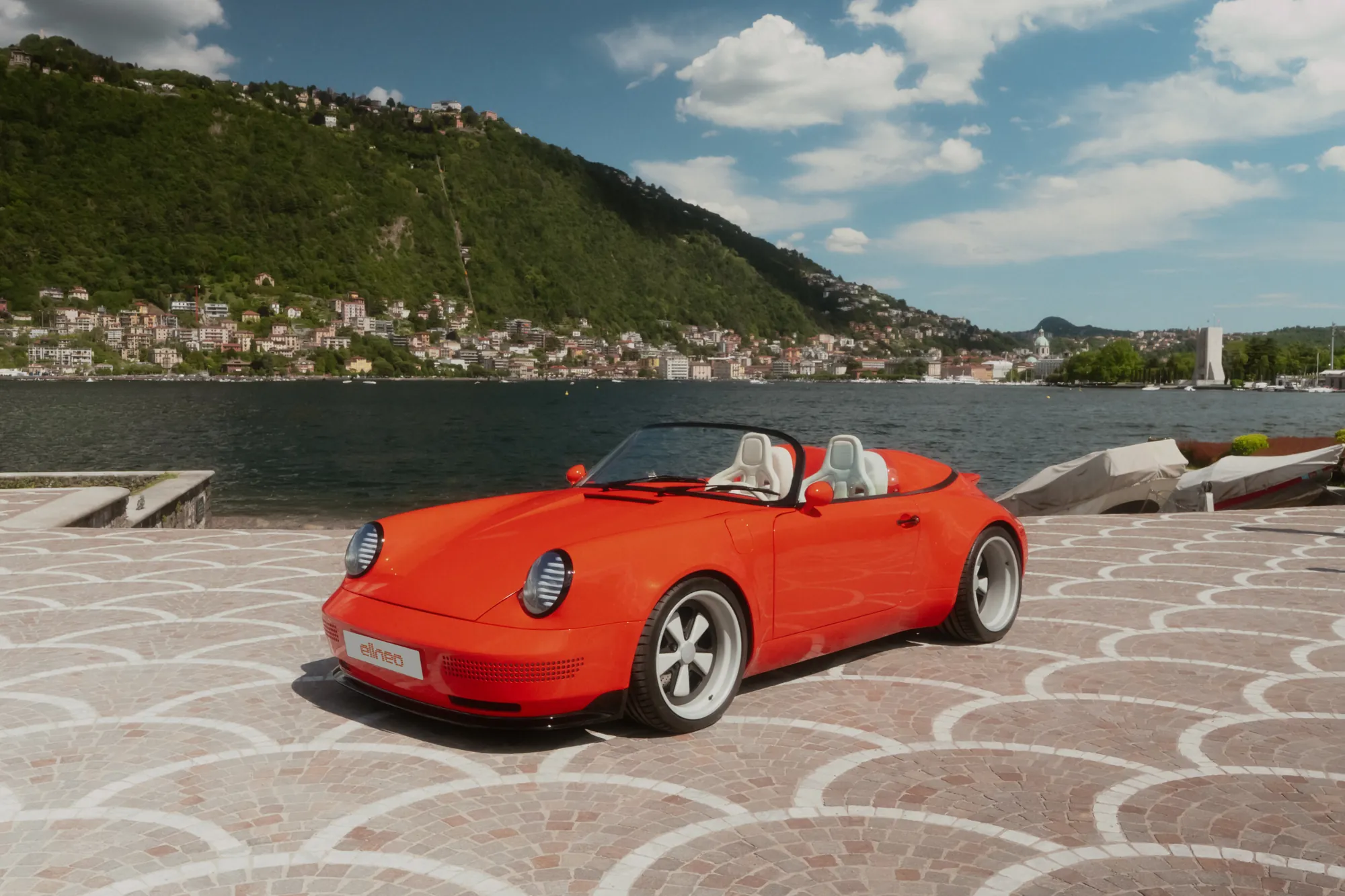 The Funkster facing the camera on fan-patterned cobbles by Lake Como, its shuttered headlights catching the light